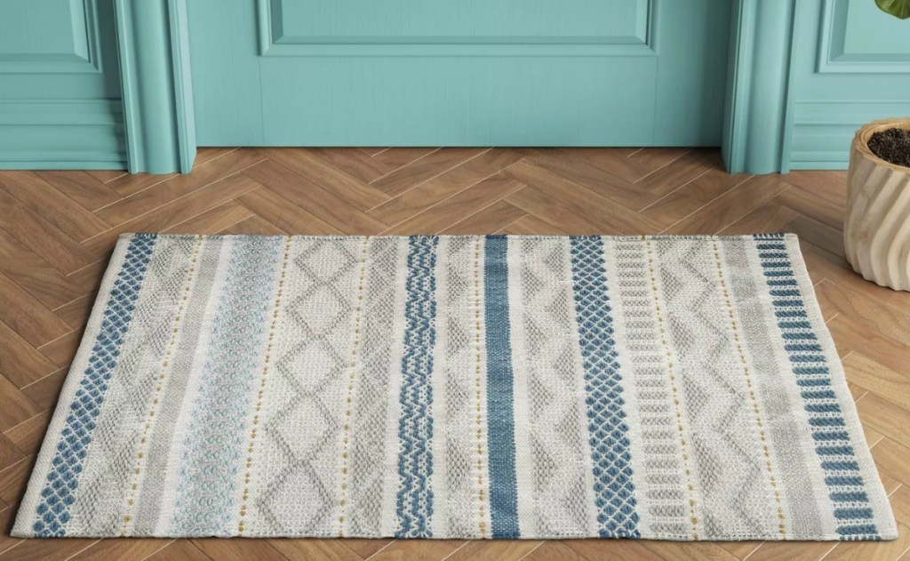 Blue and grey small area rug outside a teal colored door