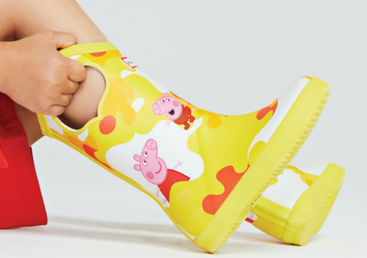 Child putting on yellow Peppa Pig rainboots