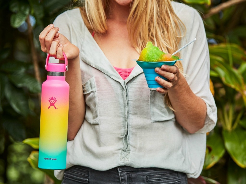 woman holding rainbow Hydro Flask in one hand and snocone in the other
