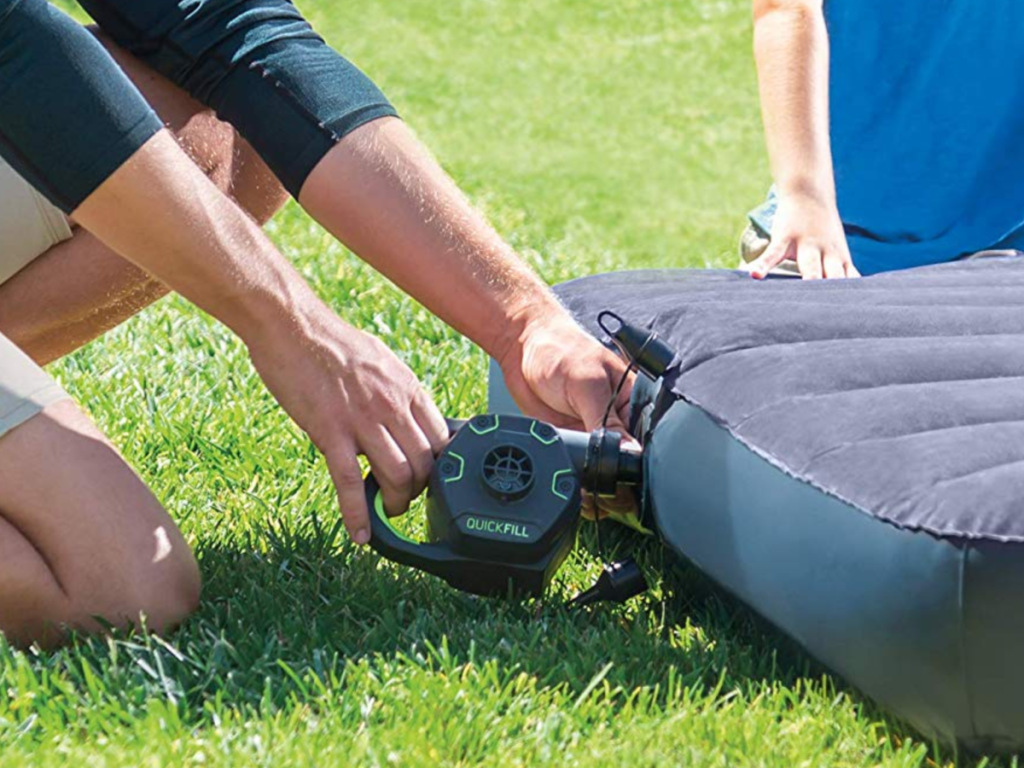 Intex Quick-Fill Rechargeable Air Pump being used on an air mattress by a man on grass.