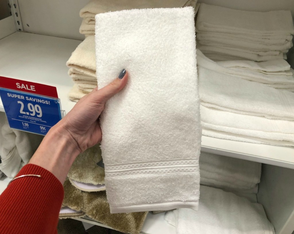 Hand holding single white hand towel in store at JCPenney