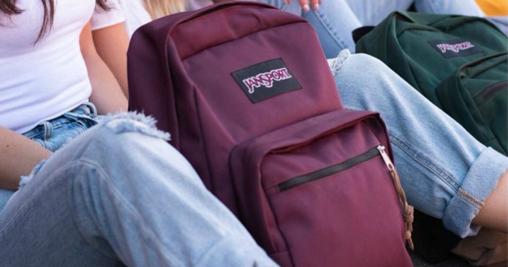 Teens leaning against the wall outside with their JanSport brand backpacks