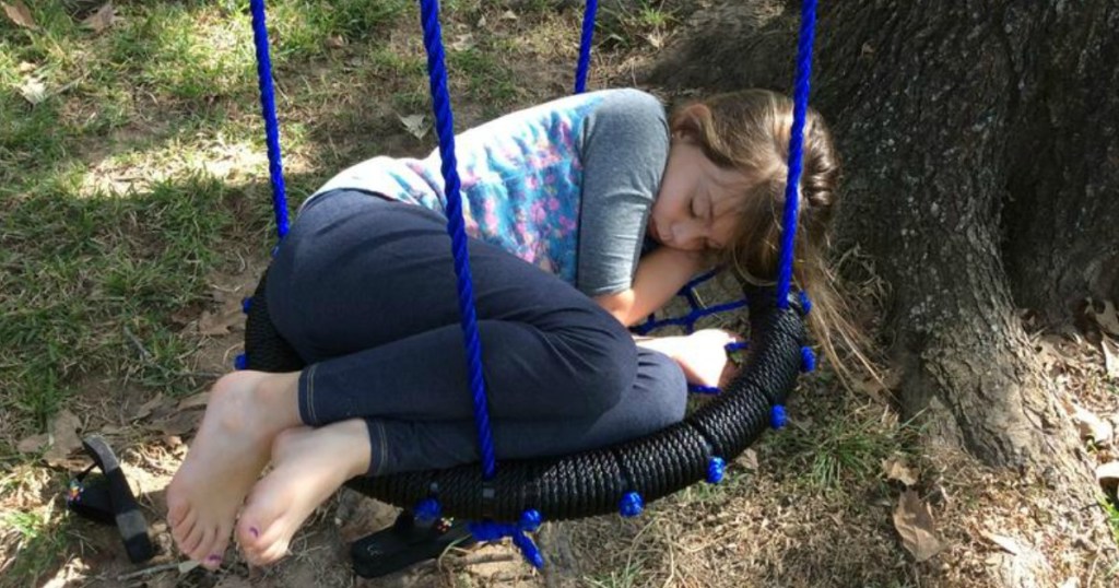 Young girl asleep in a blue web tree swing