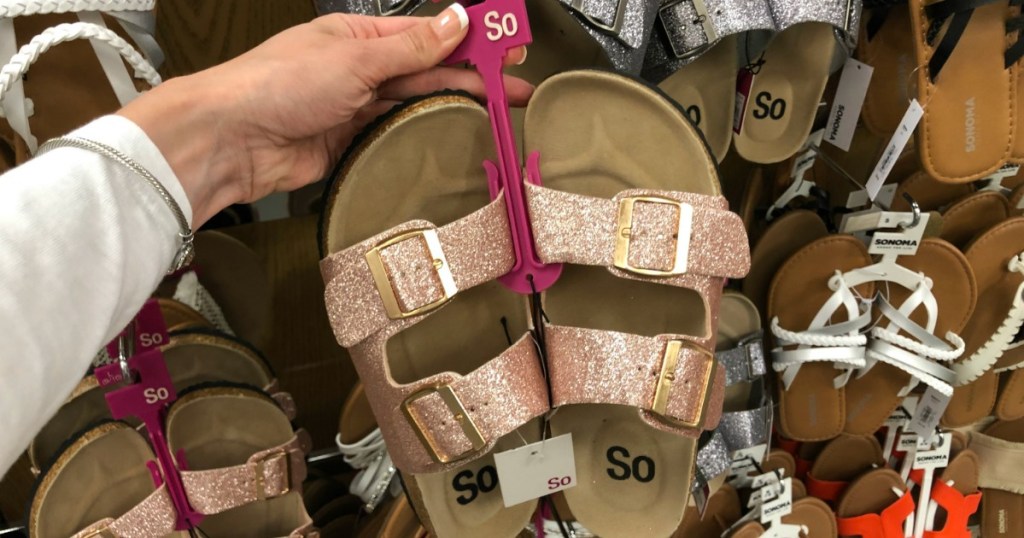 Woman holding up pair of SO Slide Sandals at Kohl's