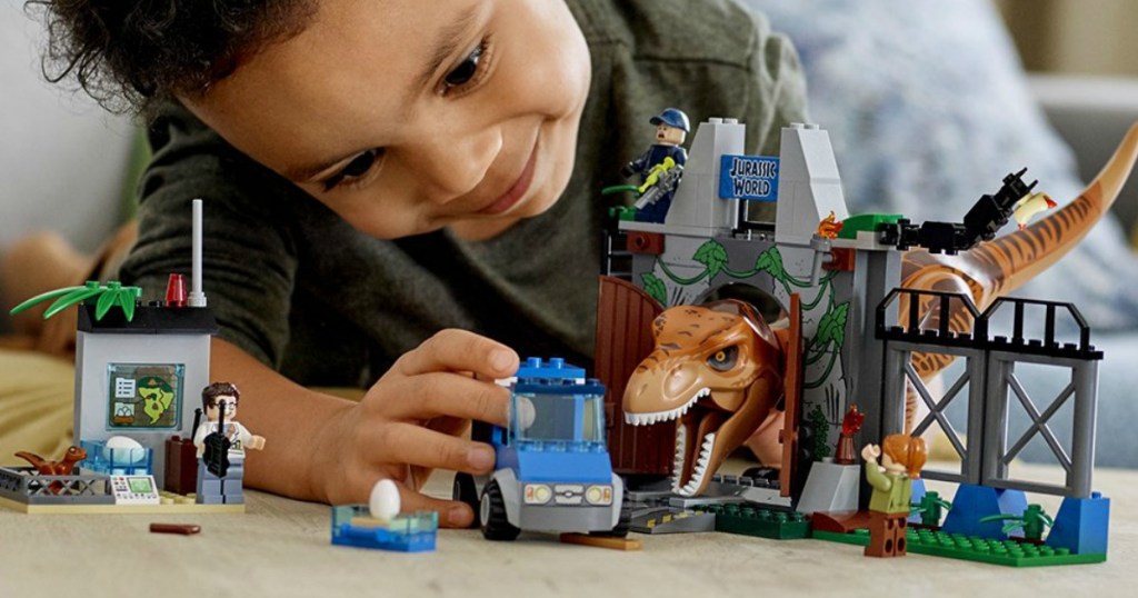 boy playing with a LEGO set, truck, and dinosaur