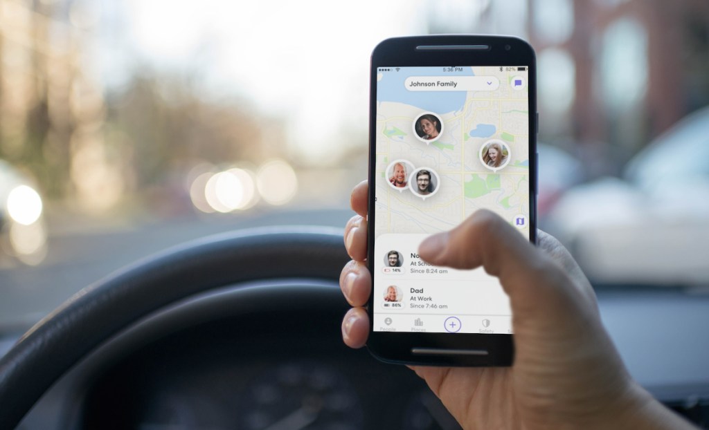 hand holding phone in car with family tracking app life 360 app on screen