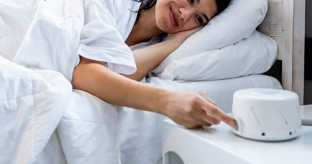 woman pushing button on Marpac Sound Machine while lying in bed