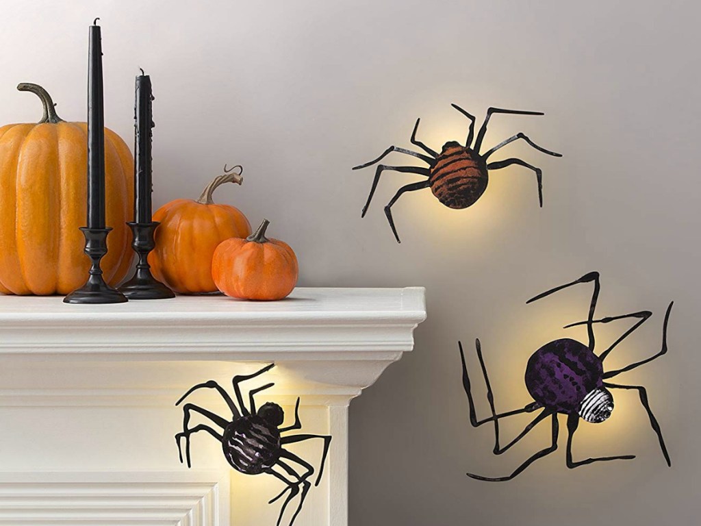 fake spiders on wall with lights behind them next to shelf