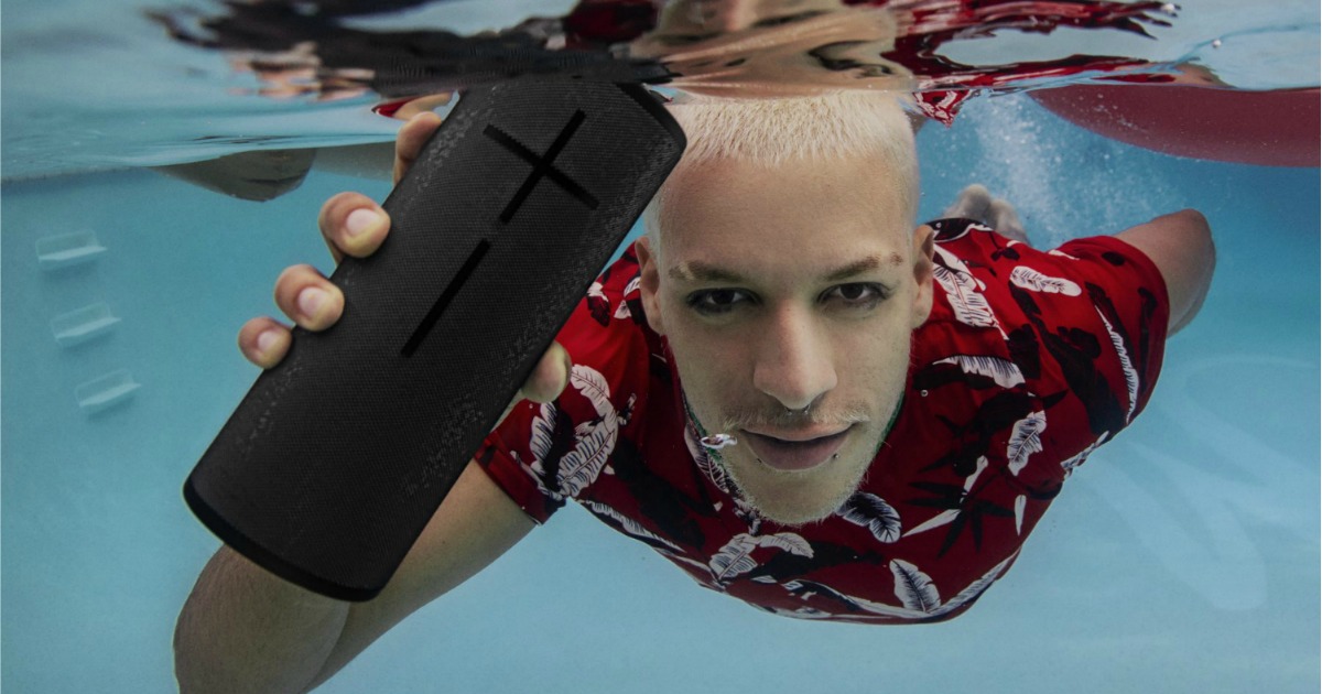 Guy swimming in pool with megaboom speaker
