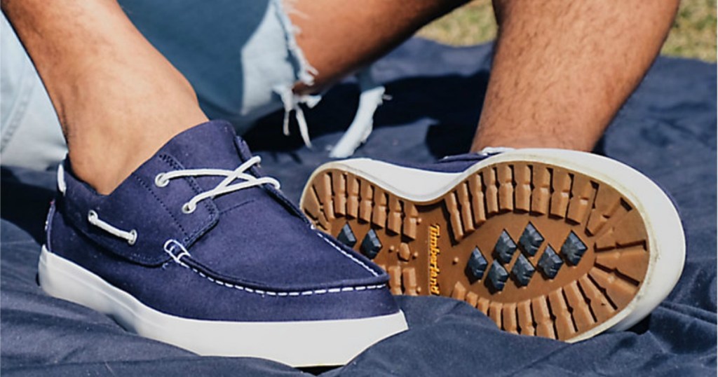 Man sitting on blanket outdoors wearing Timberland boat shoes