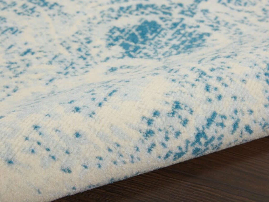 close up of a blue and white rolled up rug with wood flooring underneath