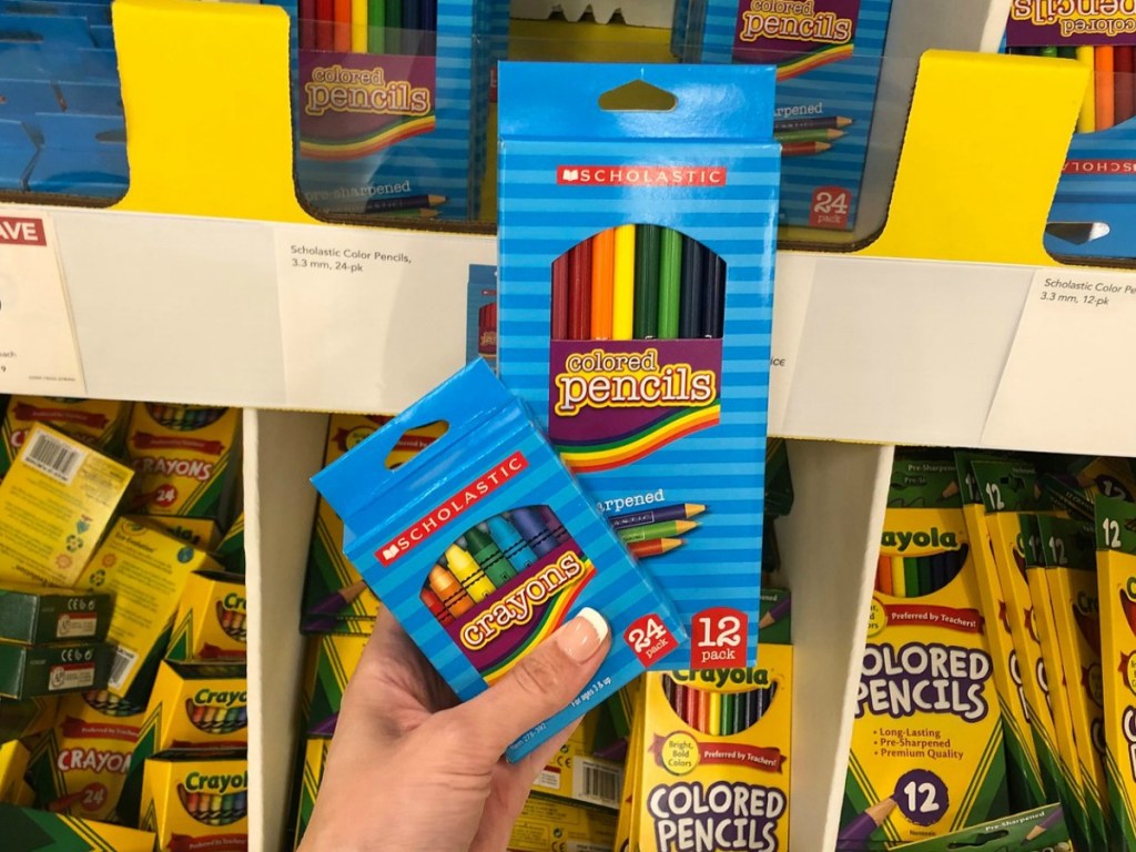 Hand holding Scholastic brand crayons and colored pencils