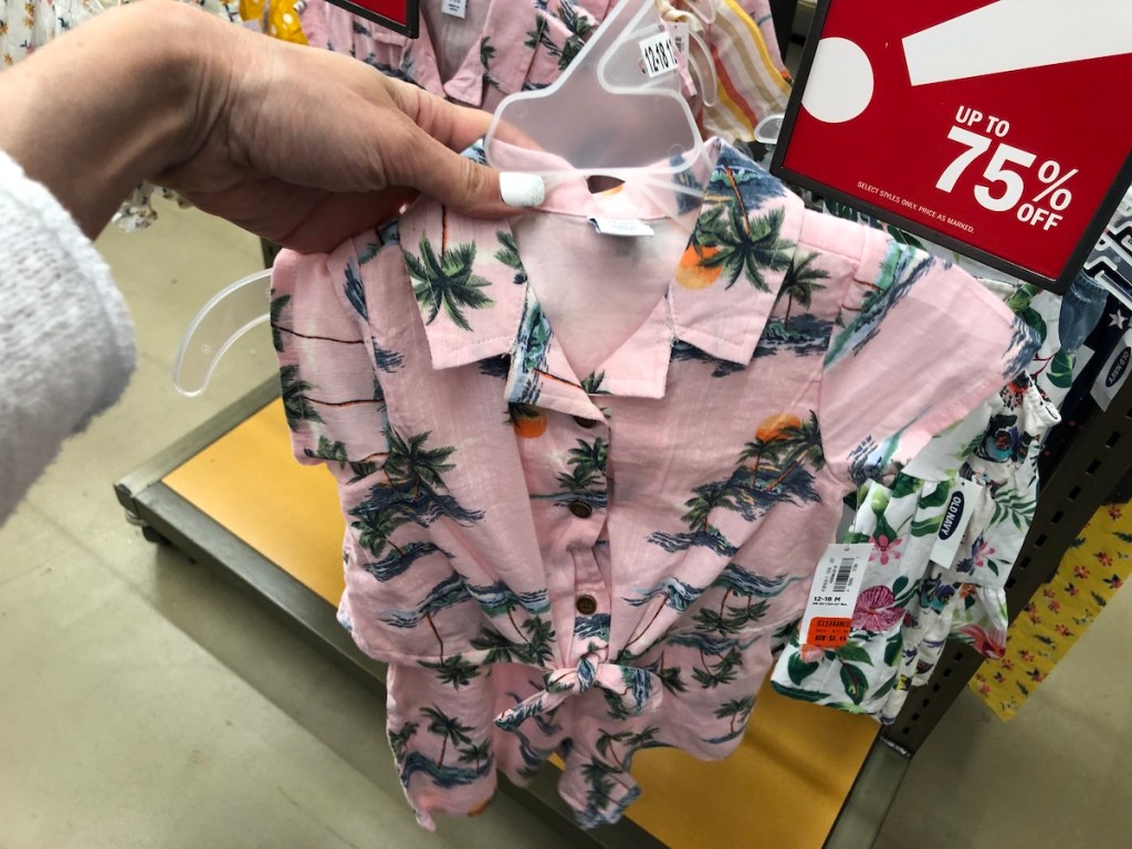 womans hand holding pink hawaiian themed outfit in old navy