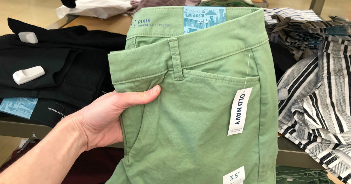 Woman holding up a pair of green women's shorts