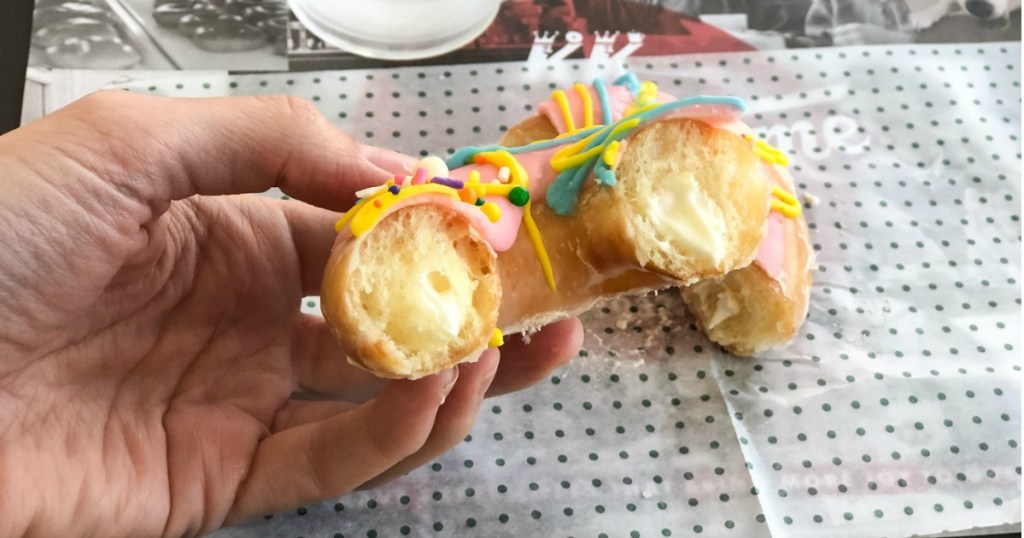 Hand holding birthday donut showing the cream filled inside