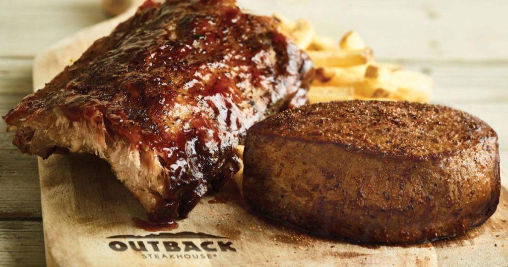 outback steak and ribs with fries on wooden cutting board