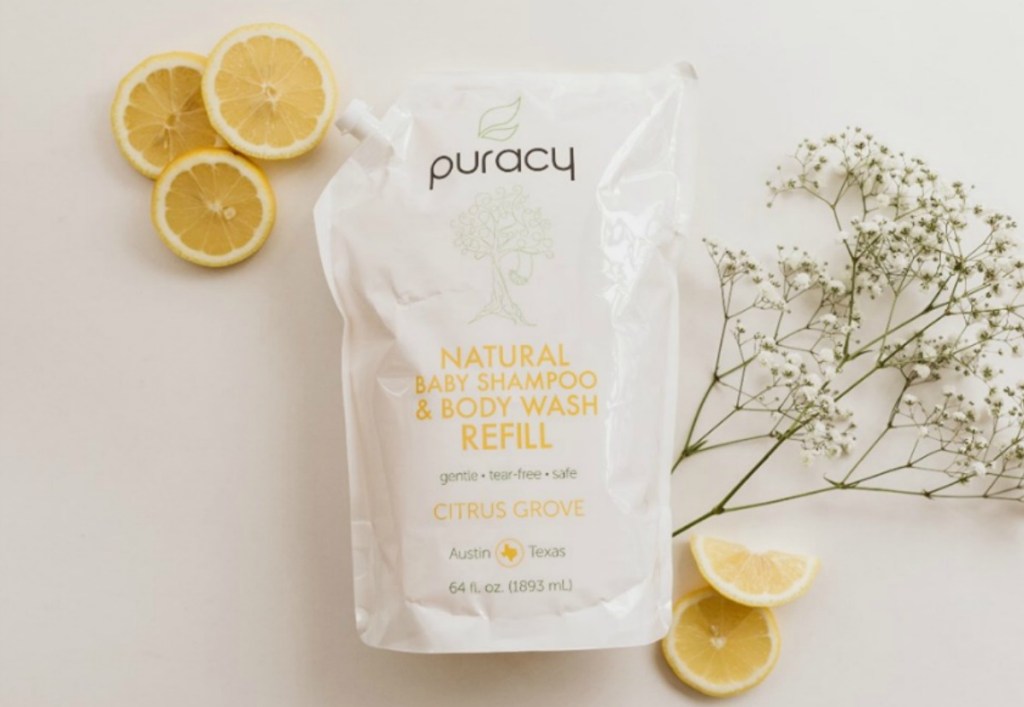 Puracy body wash refill pouch next to slced lemons and baby's breath flowers