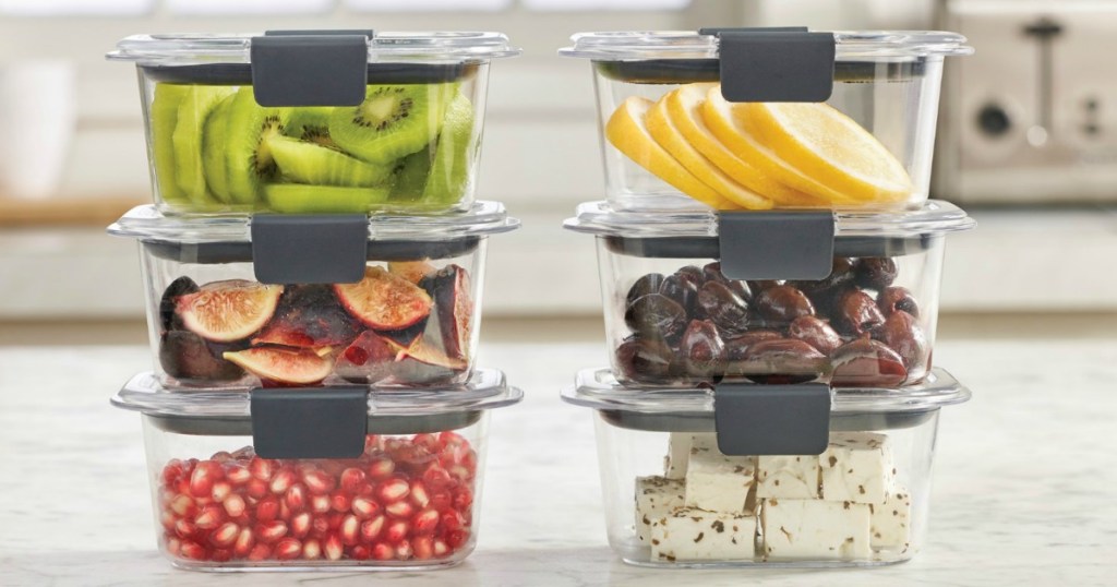 Food storage containers with fresh fruit, olives, and cheese inside on a counter top