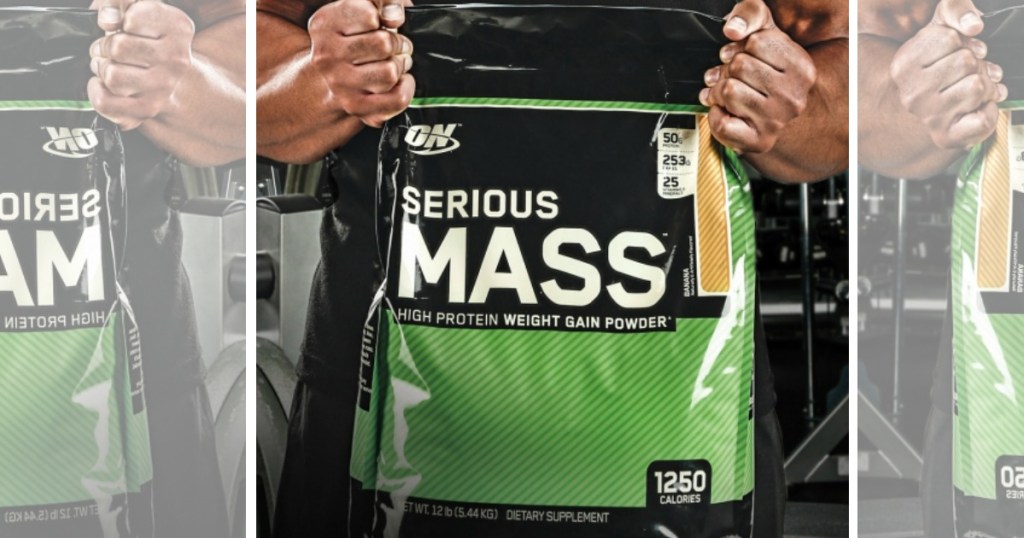 man holding bag of 12-pound bag of Optimum Nutrition Serious Mass Weight Gainer Protein Powder in gym