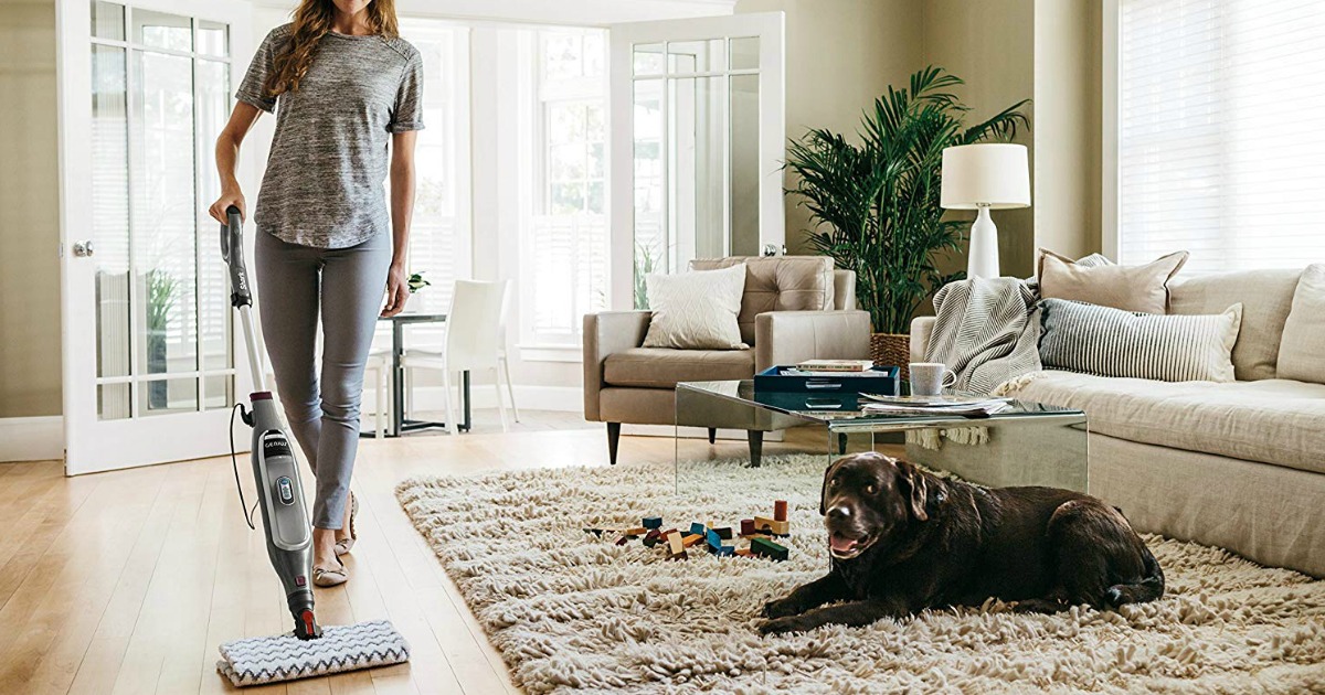 woman using a Shark Genius Pocket Steam Mop in her living room with her dog