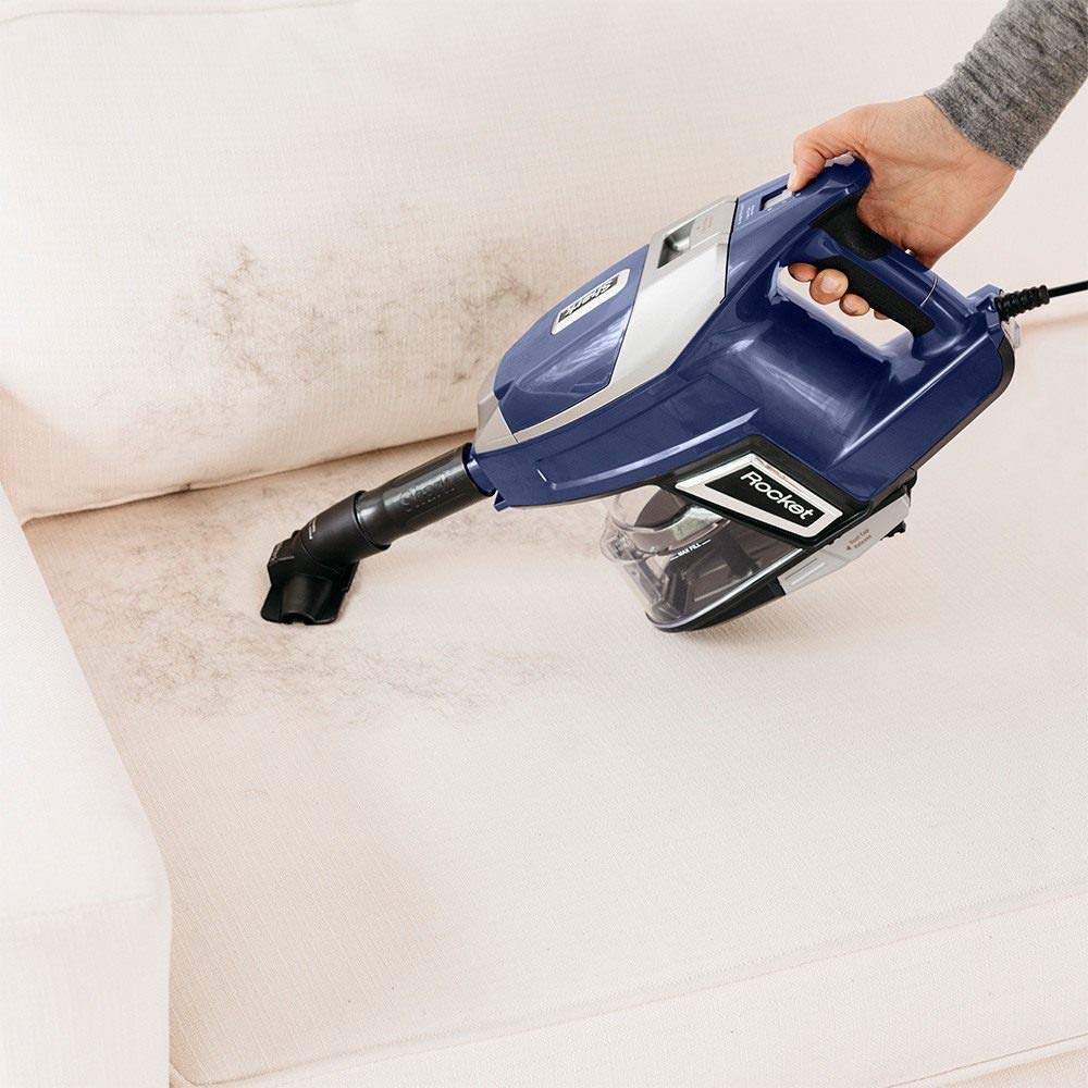 person using Shark vacuum to clean pet hair off a couch