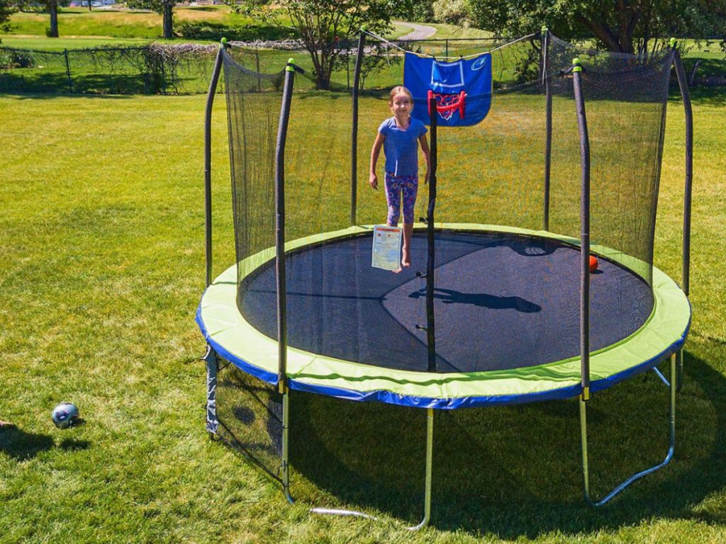 girl jumping on Skywalker 12’ Round Sports Arena Trampoline with Enclosure