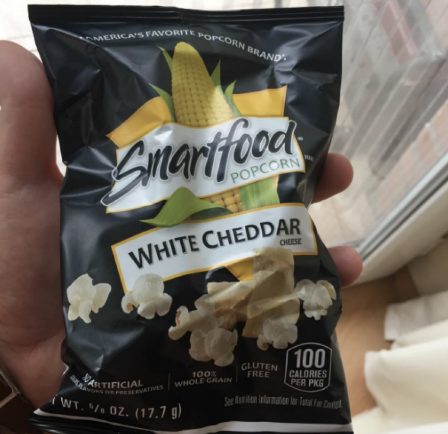 Person holding up bag of Smartfood White Cheddar Popcorn