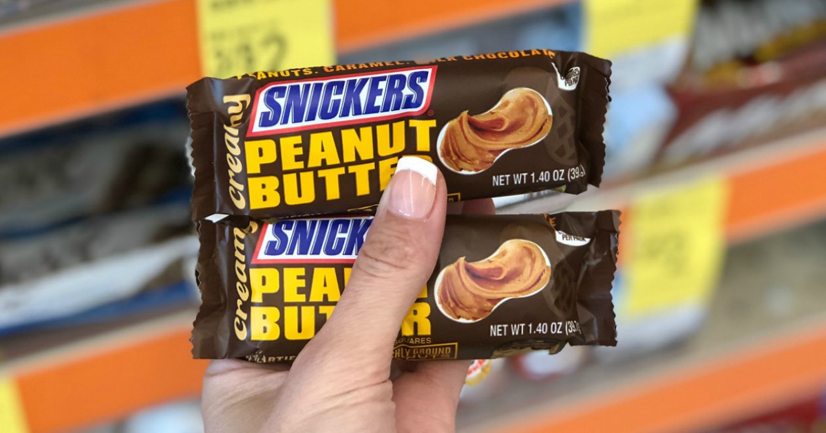 Two Snickers-brand candy bars in hand in the store