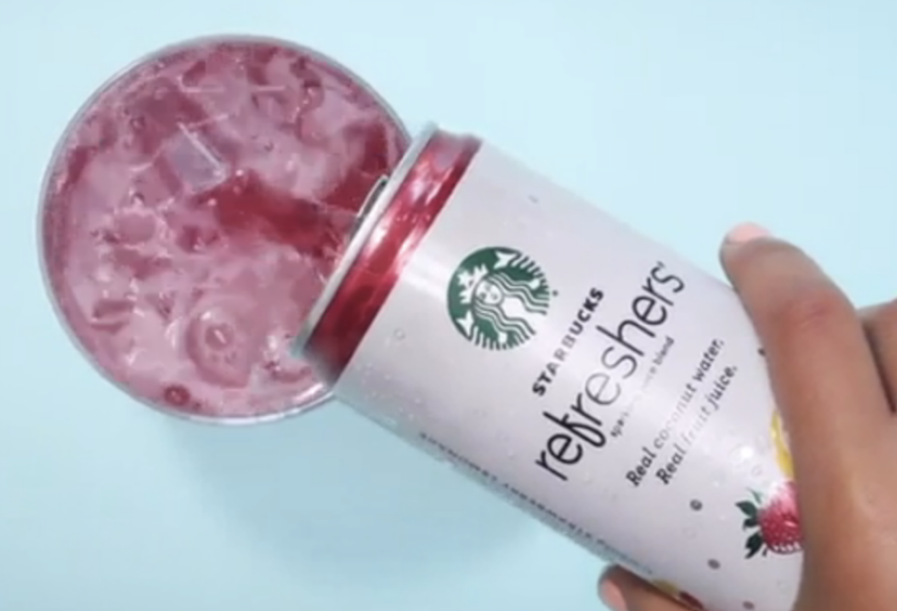 hand holding can of Starbucks Refreshers pouring it into a glass