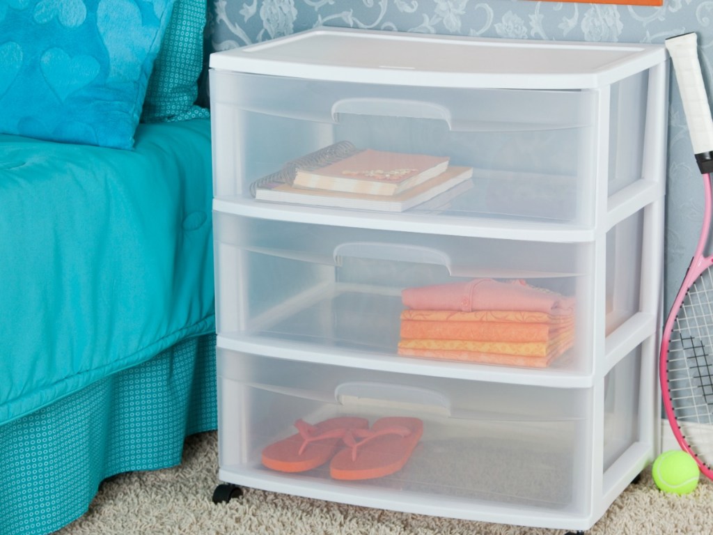 white plastic shelf next to bed with teal covers