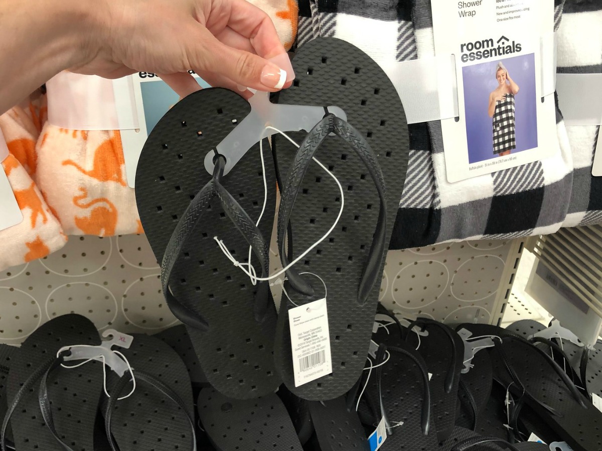 woman holding black shower flip flops at Target store