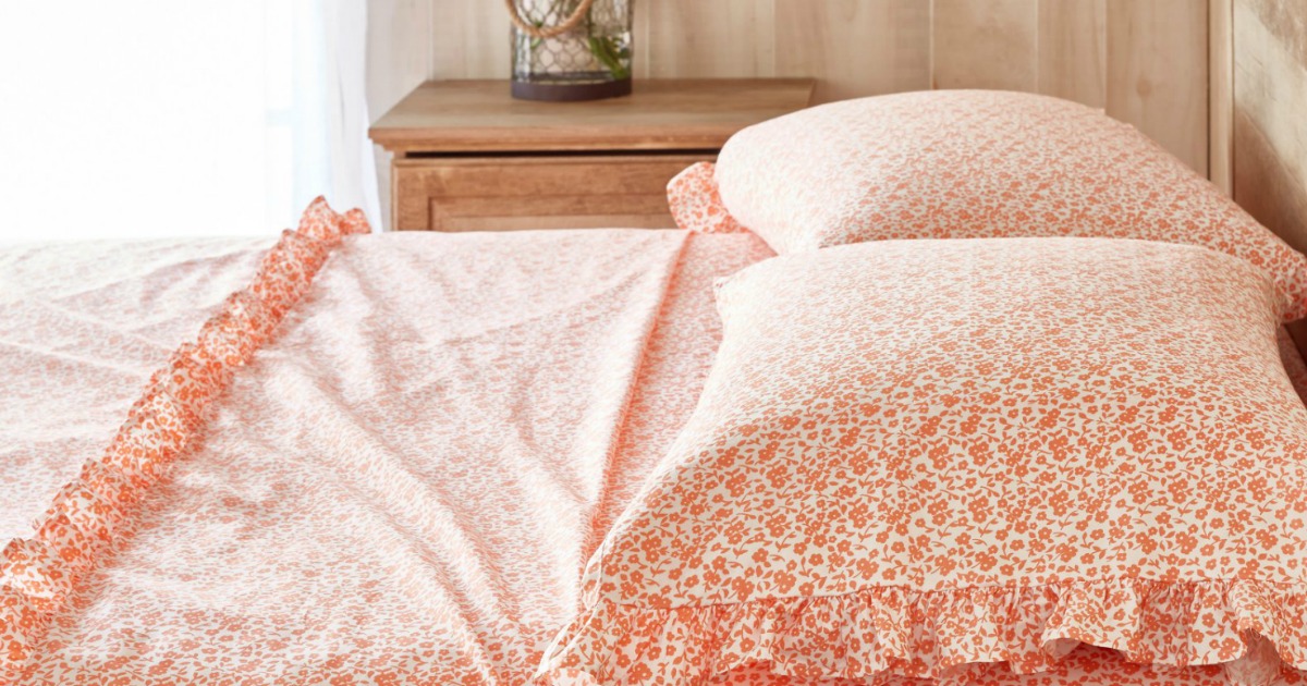 orange sheets on a bed by a window