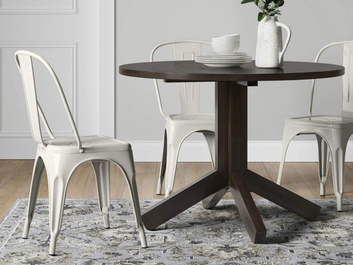 brown round table with three white chairs surrounding it 