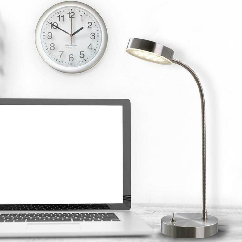 Chrome lamp on desk top with computer and clock
