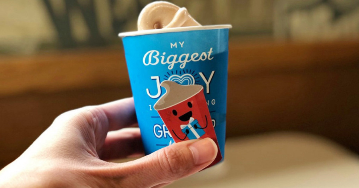 hand holding a wendy's frosty key tag in front of a Frosty in a blue cup