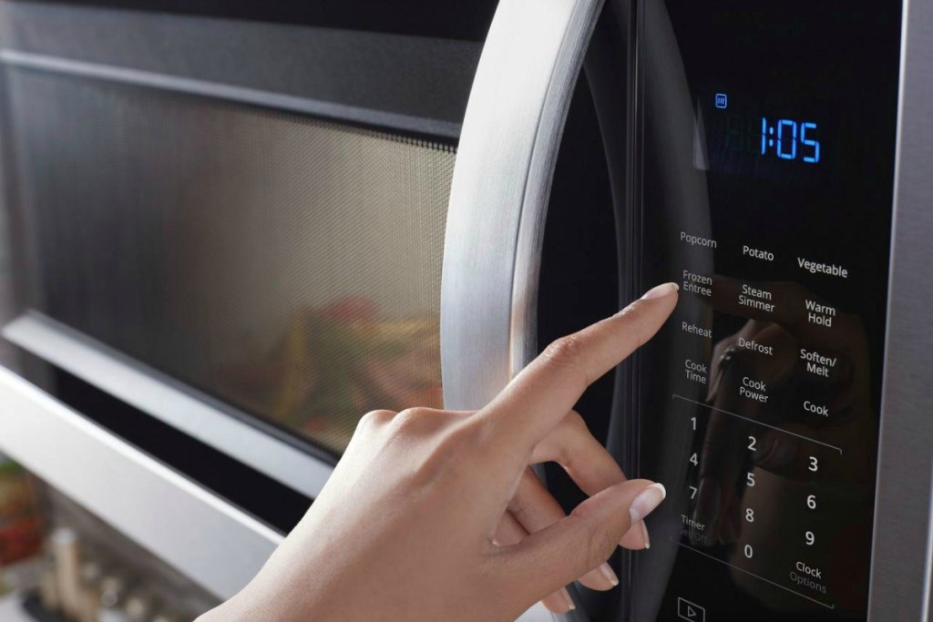 close up of a woman pushing the buttons on a microwave keypad