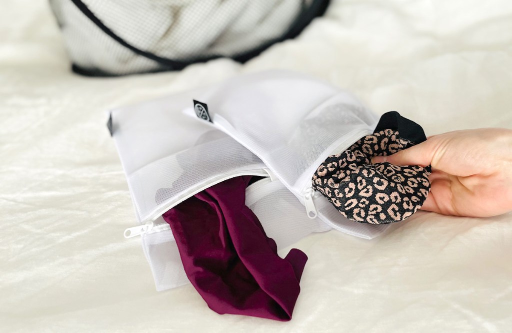 hand holding leopard garment from laundry bag for laundry room organization