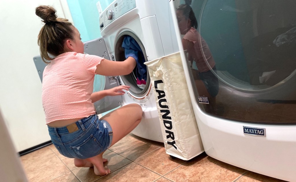 girl putting laundry in washer with laundry basket in between appliances