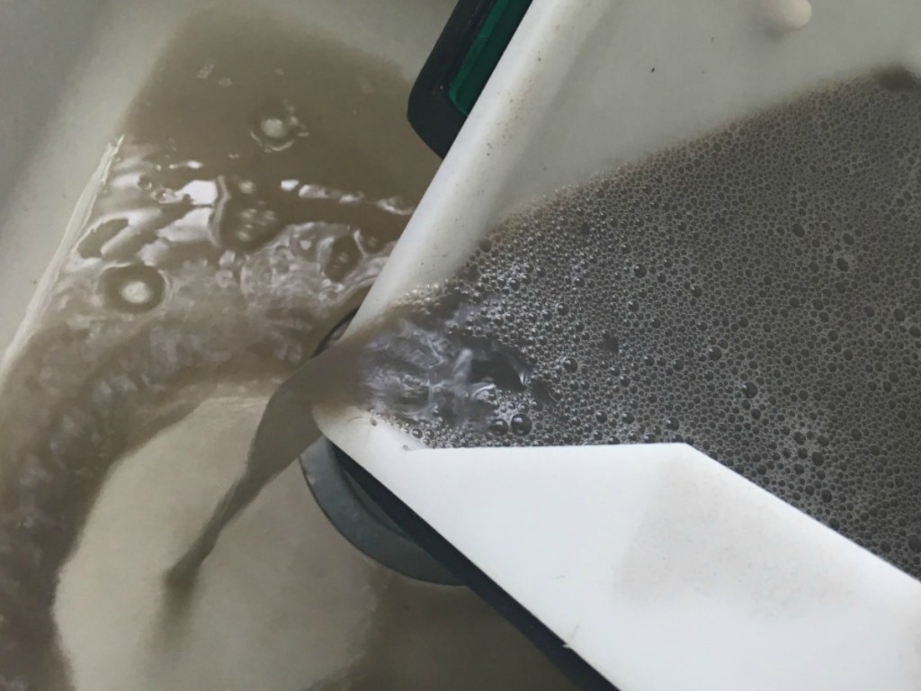 emptying bucket of dirty water into sink
