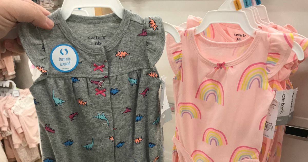 closeup of two baby rompers being held in store