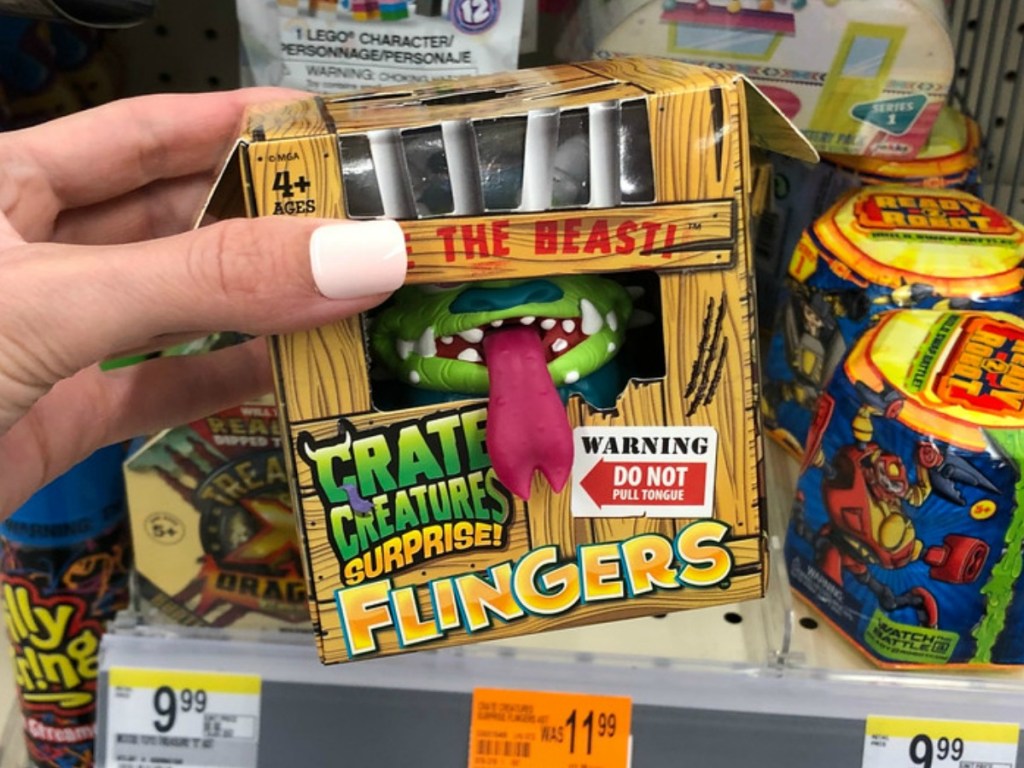hand holding toy with monster in little crate in store