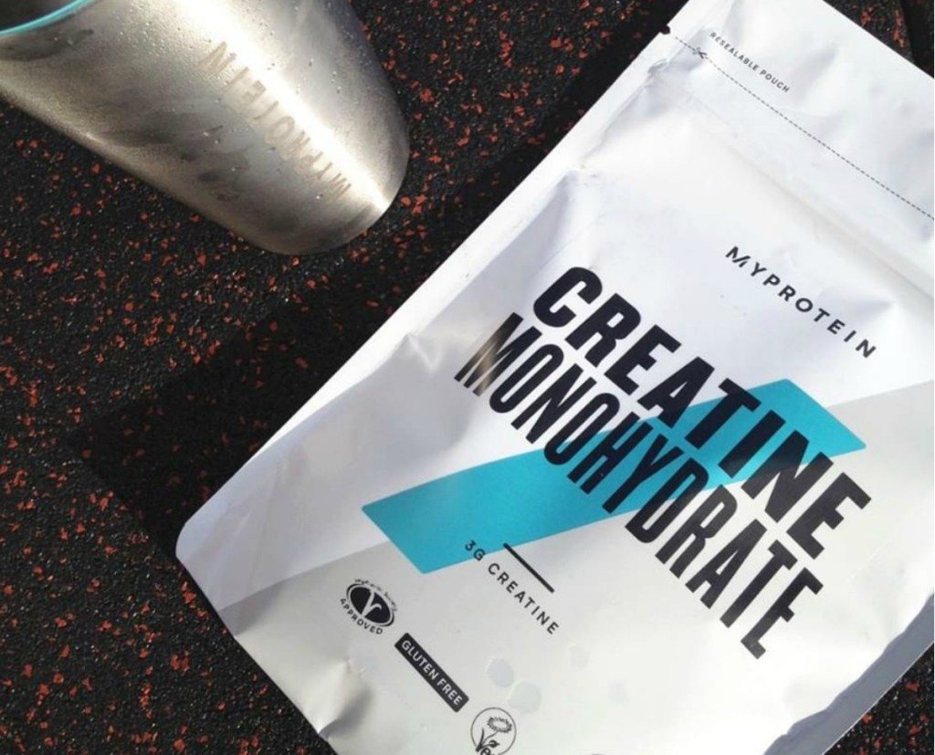 Creatine Monohydrate on table next to stainless steel bottle