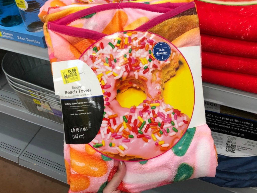 hand holding donut shaped pink beach towel by store display