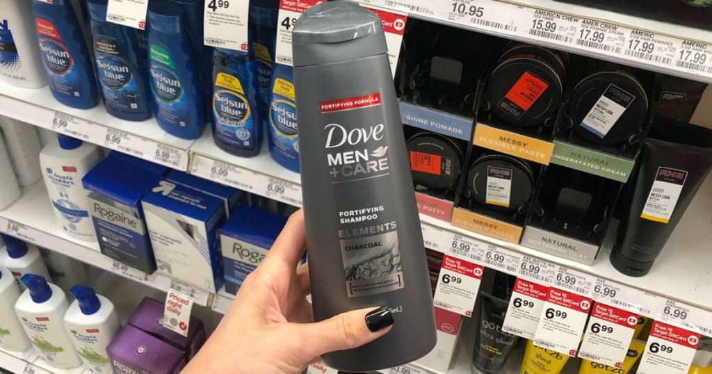 hand holding bottle of men's shampoo by store display