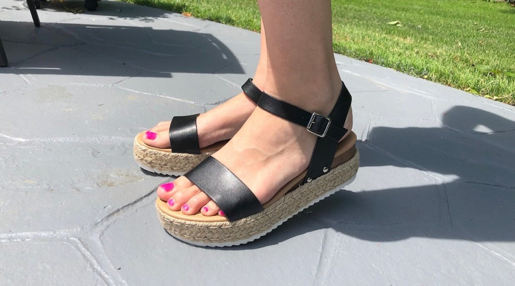 feet wearing wedge sandals black straps 
