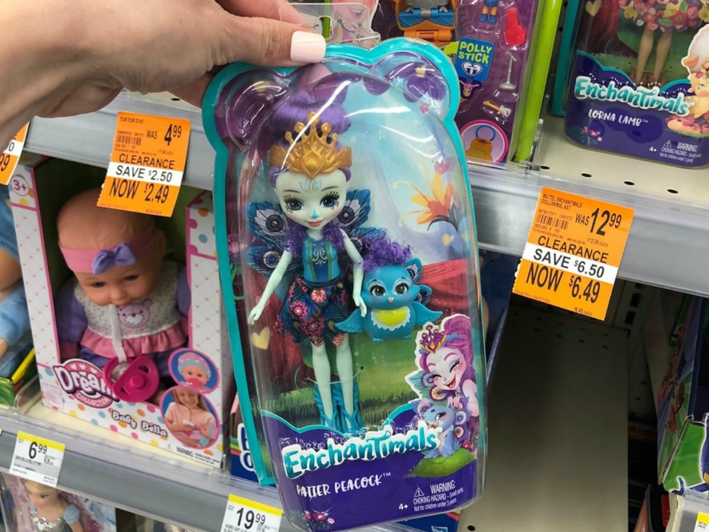 hand holding a package with doll in it in front of store display