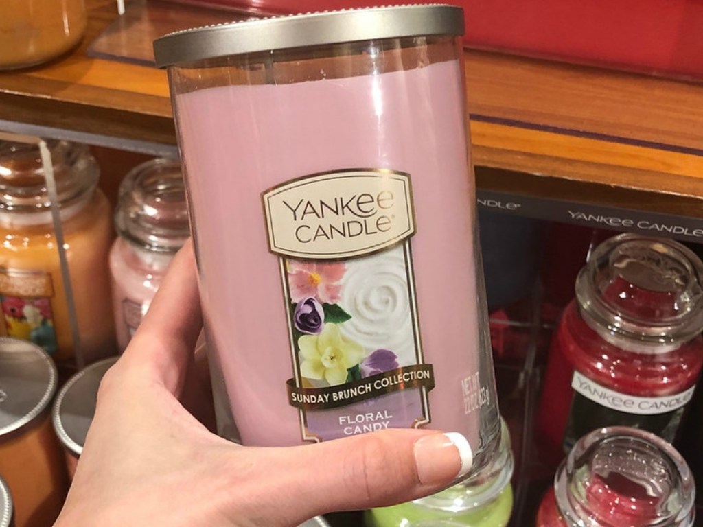 hand holding large pink candle by store display