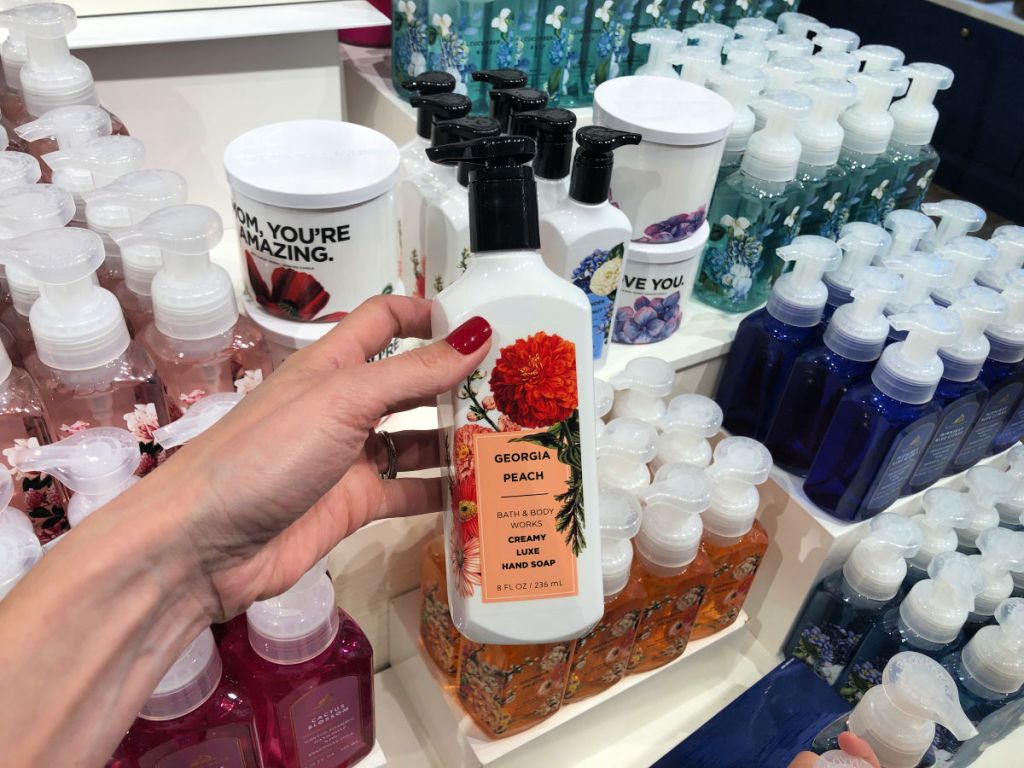 woman hand holding georgia peach bath and body works hand soap in store