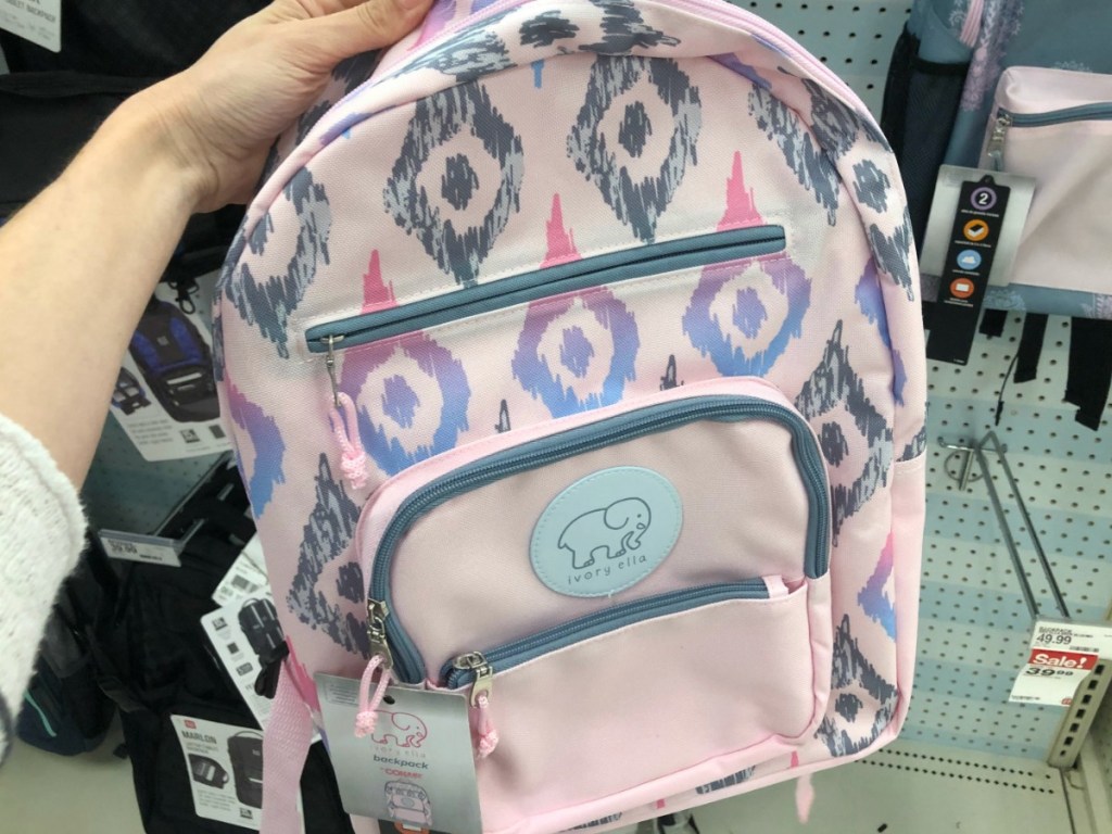 hand holding pink backpack in front of store display