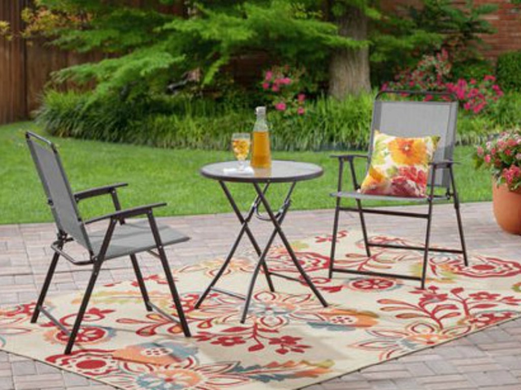 outdoor chairs and small table on rug by grass